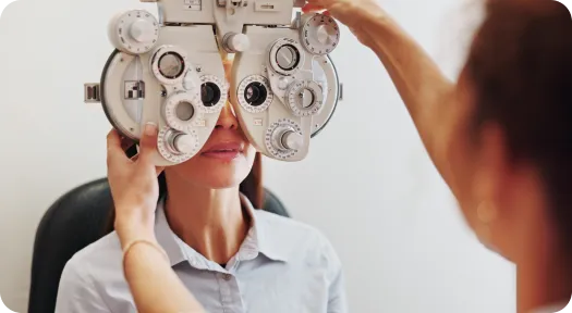 Patient undergoes an eye exam as a phoropter is adjusted for vision testing by an optometrist (or clinician).