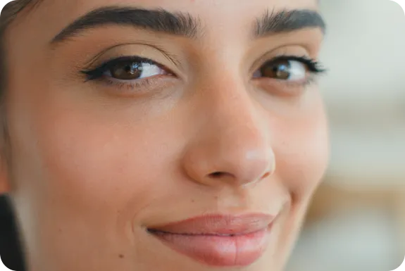 Close-up portrait of a smiling woman with dark hair and brown eyes.